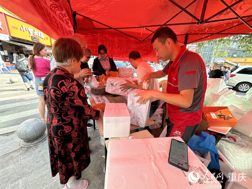 劉琦（右三）在快遞點(diǎn)將鹵鵝打包郵寄。人民網(wǎng)記者 劉政寧攝