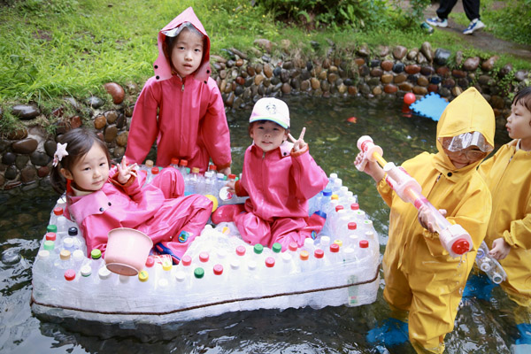 孩子們?cè)谧约河脧U舊瓶子做的小船上玩得不亦樂(lè)乎。唐文蕤攝