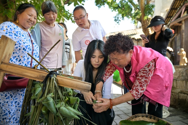 游客在當(dāng)?shù)鼐用竦闹笇?dǎo)下包粽子。綦江區(qū)委宣傳部供圖