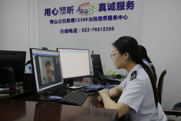 在秀山縣稅務(wù)局12366納稅繳費(fèi)服務(wù)中心，稅務(wù)人員正通過虛擬窗口與企業(yè)辦稅人員視頻連線，辦理跨區(qū)域涉稅業(yè)務(wù)。張?chǎng)┗輸z