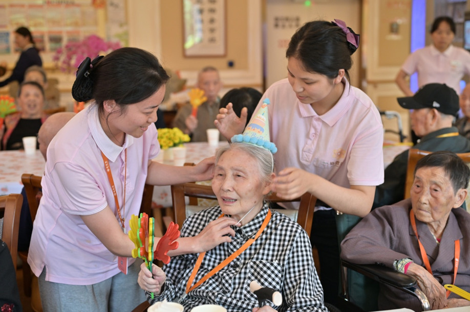 養(yǎng)老機構(gòu)工作人員為壽星老人們戴上生日帽，情暖老人心。程佩玉攝