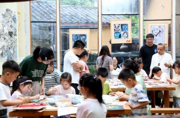 孩子們在大學(xué)生志愿者的指導(dǎo)下制作版畫。張夢寒?dāng)z