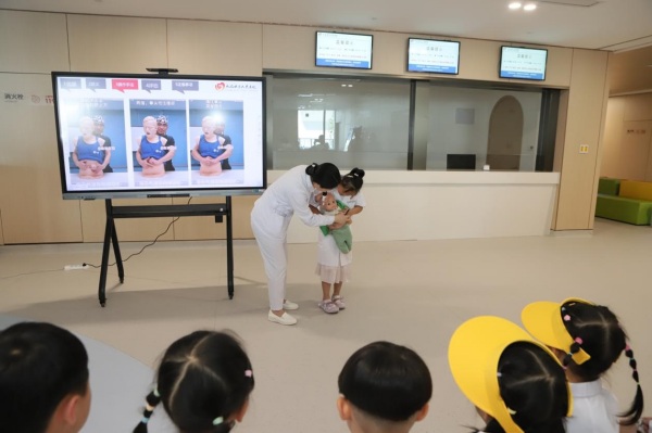 萌娃在醫(yī)院工作人員的指導下學習海姆立克急救方法。趙海攝