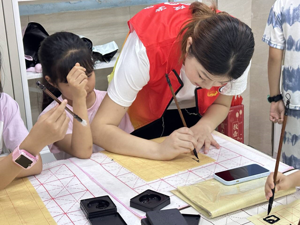 志愿者幫助孩子們?cè)谀阒懈惺軅鹘y(tǒng)文化魅力。唐彬貴攝