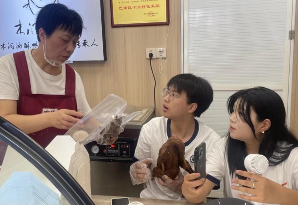 店內(nèi)負(fù)責(zé)人向直播間觀眾展示改良包裝。重慶財(cái)經(jīng)學(xué)院供圖