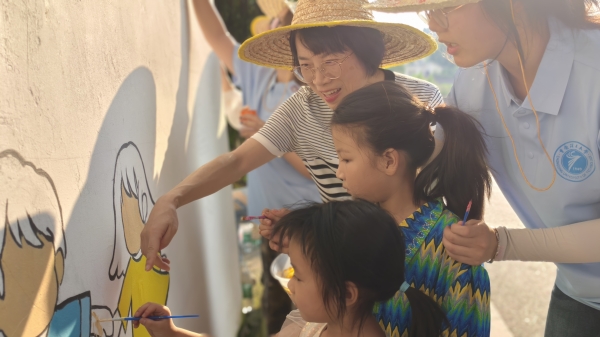 實(shí)踐團(tuán)師生指導(dǎo)小朋友參與繪制法治墻。重慶理工大學(xué)供圖