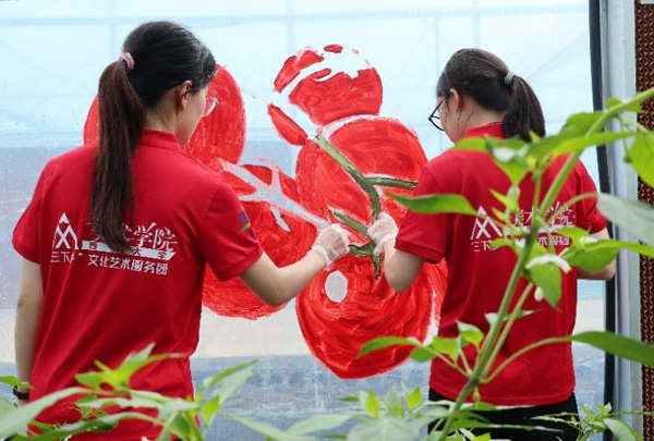 志愿者在大棚外立面進行主題繪畫創(chuàng)作。西南大學供圖
