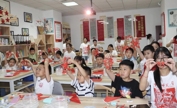 實(shí)踐團(tuán)成員與孩子們共同創(chuàng)作剪紙作品。重慶師范大學(xué)美術(shù)學(xué)院供圖