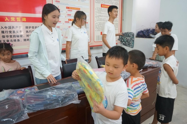 服務(wù)團(tuán)成員給小朋友發(fā)放紀(jì)念品。李思諺攝