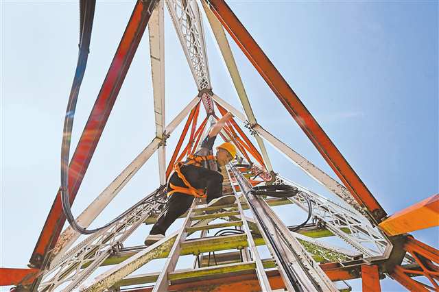 7月17日，重慶江北國際機(jī)場停機(jī)坪，導(dǎo)航技術(shù)室巡查員李遠(yuǎn)望在天線塔架上進(jìn)行例檢。