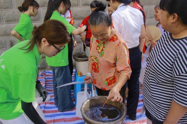 踐行團(tuán)成員引導(dǎo)居民體驗(yàn)非遺活動。重慶電力高等?？茖W(xué)校供圖