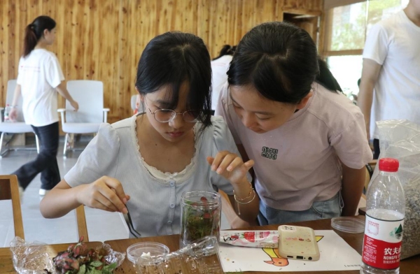 服務(wù)團(tuán)成員引導(dǎo)小朋友親手設(shè)計生態(tài)瓶布局。重慶師范大學(xué)供圖