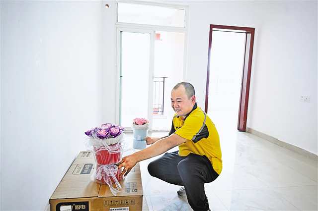 7月16日，空港樂園公租房小區(qū)，外賣員劉進波迫不及待地將妻子做的手工花先放進新家。