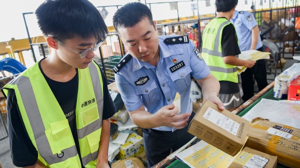 民警為快遞貼上反詐宣傳小貼紙。南岸區(qū)公安分局供圖