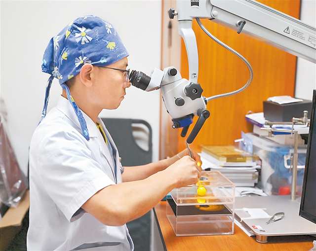 周建軍在顯微鏡前利用葡萄練習(xí)傷口縫合。