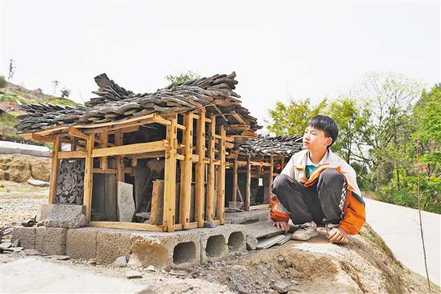 鄒君潔和他復(fù)刻的吊腳樓。（本組圖片由市委文明辦提供）