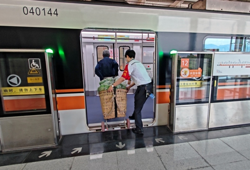 工作人員幫菜農(nóng)將背簍運(yùn)進(jìn)地鐵車廂。重慶軌道四號線建設(shè)運(yùn)營有限公司供圖