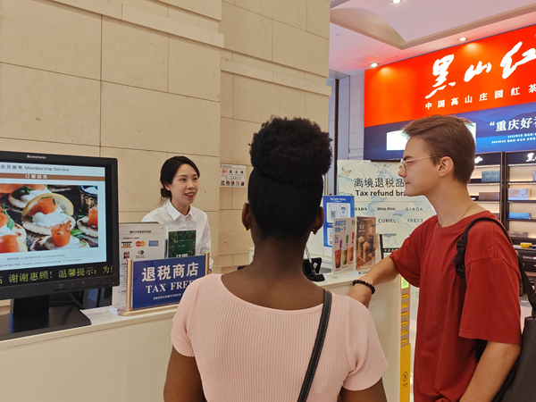 在解放碑的重慶環(huán)球金融中心離境退稅服務(wù)臺(tái)，工作人員為來(lái)自俄羅斯和西非多哥的游客介紹離境退稅“即買(mǎi)即退”服務(wù)。徐佑君攝