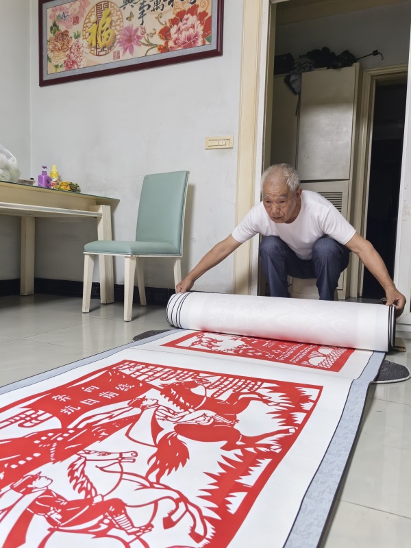 郭文友展示剪紙作品《銘記歷史 振興中華》。江津區(qū)委宣傳部供圖